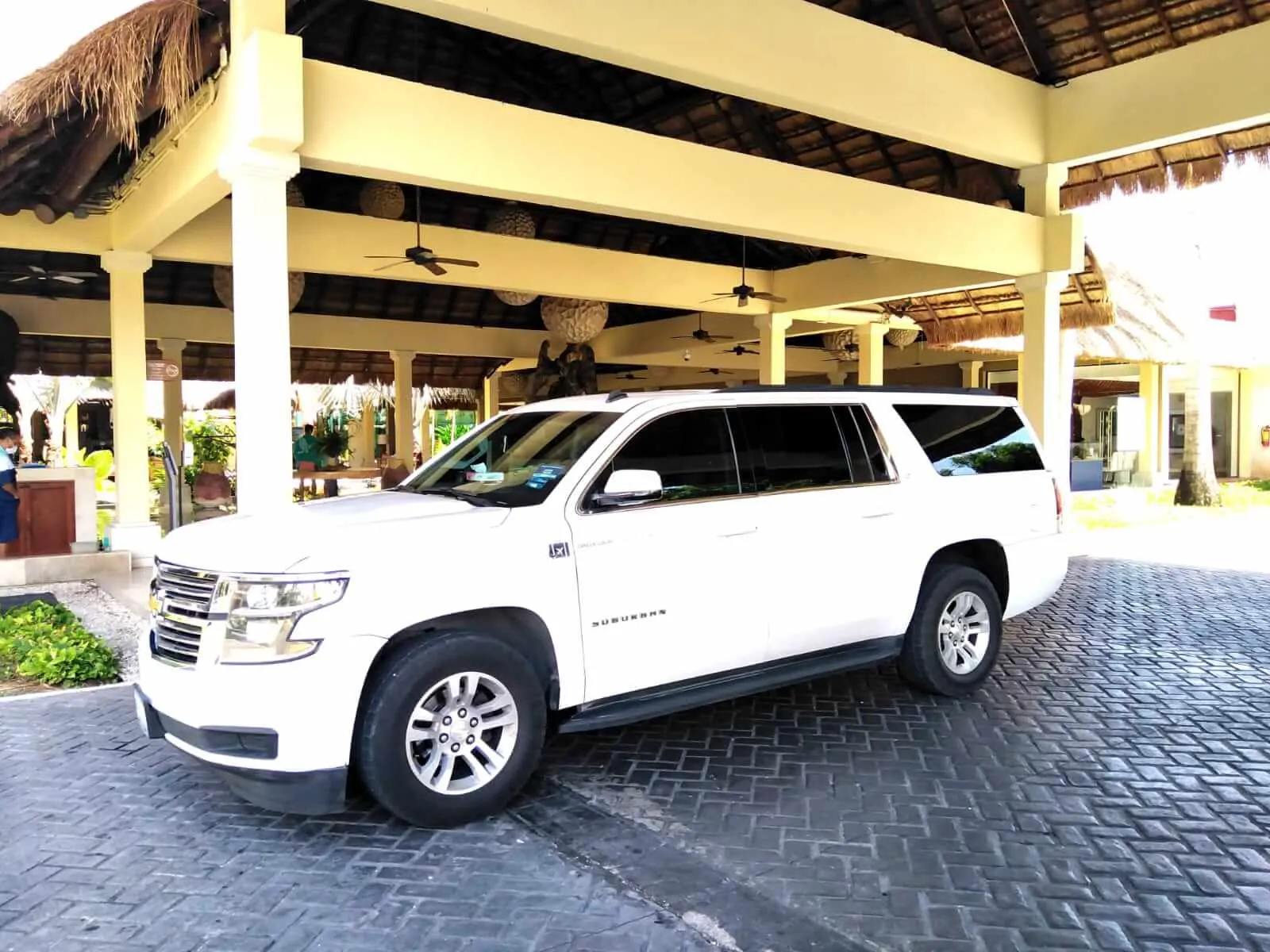 White luxury SUV parked in front of hotel lobby